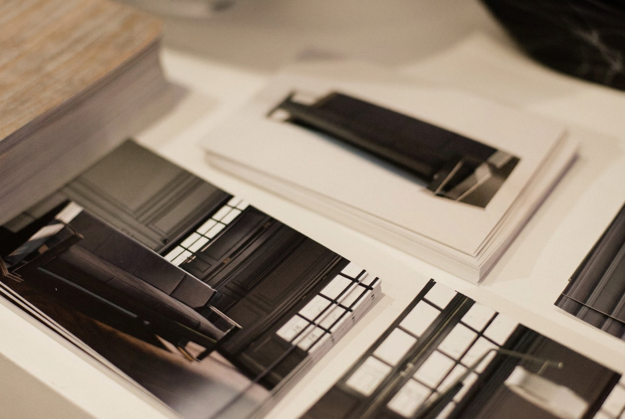 Printed interior photography prints and a design book laid out on a white studio table